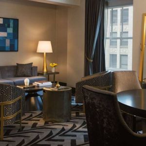 Lounge within a guest room of The Allegro Royal Sonesta Hotel Chicago Loop, including sofa, armchairs, coffee tables, and a window.