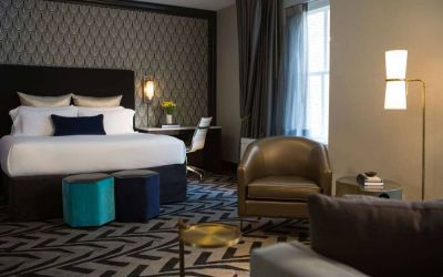 The Allegro Royal Sonesta Hotel Chicago Loop double bed guest room, furnished with workspace desk and chair, window, and an armchair and coffee table.