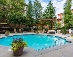 Sonesta ES Suites Atlanta - Perimeter Center’s round outdoor pool has potted plants and sun loungers nearby, with tables and chairs close at hand.
