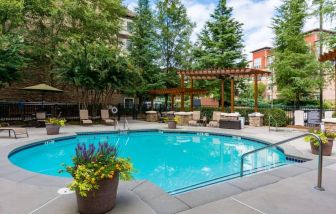 Sonesta ES Suites Atlanta - Perimeter Center’s round outdoor pool has potted plants and sun loungers nearby, with tables and chairs close at hand.