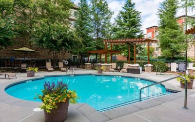 Sonesta ES Suites Atlanta - Perimeter Center’s round outdoor pool has potted plants and sun loungers nearby, with tables and chairs close at hand.