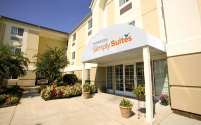 The hotel’s exterior features flowerbeds, potted plants, and trees, with nearby benches where guests can relax amid the greenery.