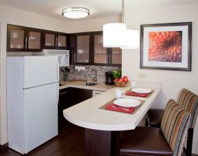 Sonesta ES Suites Atlanta Alpharetta Avalon guest room kitchen, including fridge-freezer, microwave, and kitchen table with two chairs.