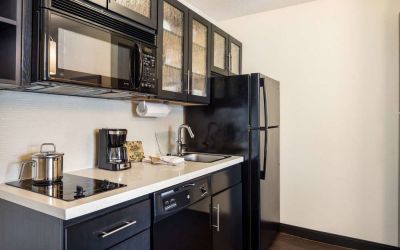 Sonesta Simply Suites Detroit Troy guest room kitchen, equipped with microwave, hob, and fridge-freezer.