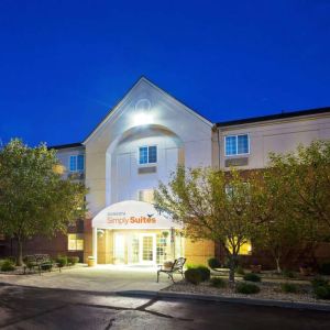 The hotel’s exterior has potted plants and benches by the front door, with trees and bushes nearby.