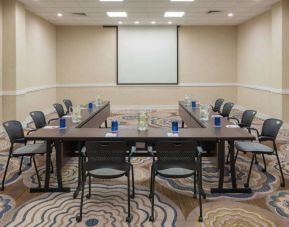Meeting room in Sonesta White Plains Downtown, with tables arranged in a U-shape, seating for 10, and a projector screen.