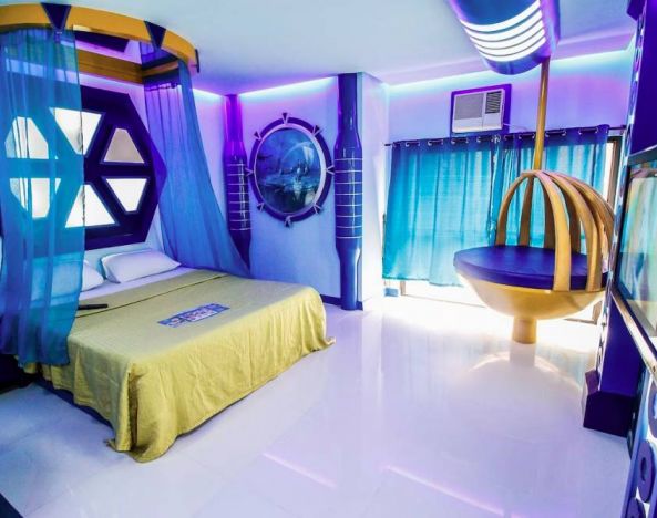 Dreamworld Araneta double bed guest room, decorated in blue, with a bedside telephone and wall-mounted TV.