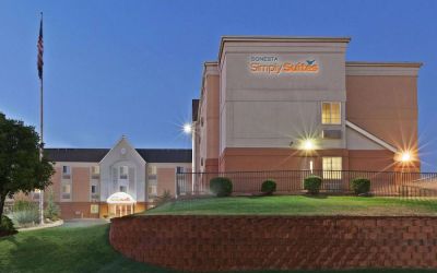 Sonesta Simply Suites Oklahoma City Airport’s exterior has a USA flag, abundant greenery including well-trimmed bushes, and the hotel chain’s name clearly indicated.