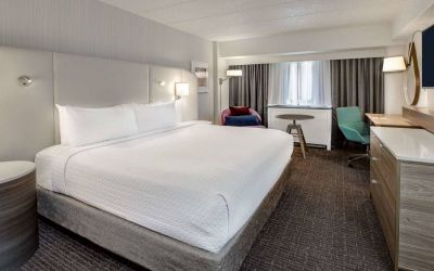 Sonesta Columbus Downtown double bed guest room, featuring armchair, window, and TV, and a workspace desk and chair.