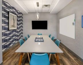 Sonesta Columbus Downtown meeting room, featuring whiteboard and wall-mounted TV, plus a long table and eight chairs.