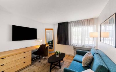 Sonesta Simply Suites Austin South guest room living area, furnished with sofa, coffee table, chair, and wall-mounted TV.