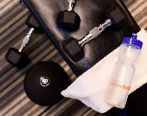 The fitness center in Sonesta Simply Suites Austin South has free weights and benches, plus towels and water.
