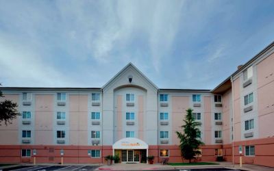 The hotel’s exterior includes disabled parking spaces close to the front door, potted plants, and a tall tree.