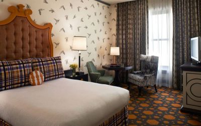 Double bed guest room in Royal Sonesta Portland Downtown, furnished with chairs and a coffee table, window, and a TV.