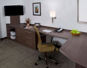 Guest room workspace in Sonesta Simply Suites Houston CityCentre I-10 West, featuring desk, chair, lamp, and telephone.