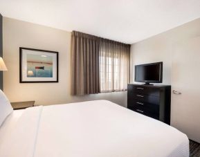 Double bed guest room in Sonesta Simply Suites Plano Frisco, featuring a window, art on the wall, and TV.