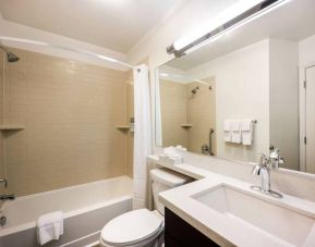 Guest bathroom in Sonesta Simply Suites Plano Frisco, including mirror and sink, lavatory, and bath equipped with a shower.