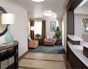Sonesta Simply Suites Plano Frisco’s lobby features a pair of armchairs, window, coffee table, and potted plants.