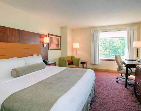 Double bed guest room in Sonesta Milwaukee West Wauwatosa, featuring armchair, window, and television.