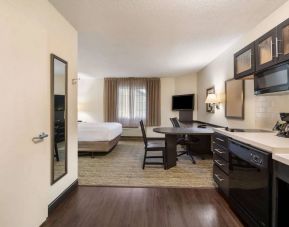 Sonesta Simply Suites Hampton double bed guest room, with kitchen, chairs, window, and a TV.