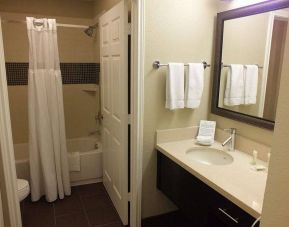 Guest bathroom in Sonesta ES Suites Dallas Las Colinas, featuring bath with a shower, lavatory, and mirror and sink.