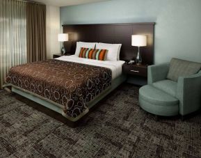 Double bed guest room in Sonesta ES Suites Dallas Las Colinas, featuring armchair, bedside lamps, and a window.