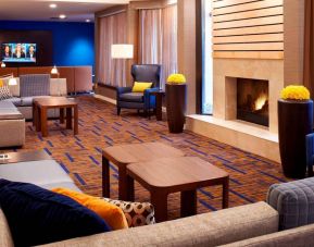 Sonesta Select Detroit Auburn Hills’ lobby lounge is furnished with sofas, armchairs, coffee tables, a fireplace and a wall-mounted TV.