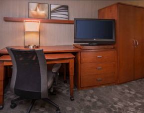 Sonesta Select Columbia guest room workspace, featuring desk, chair, and lamp, with a nearby TV.