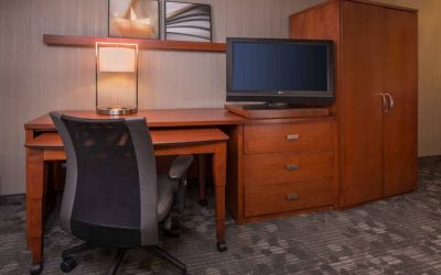 Sonesta Select Columbia guest room workspace, featuring desk, chair, and lamp, with a nearby TV.