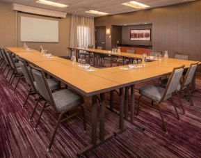 Meeting room in Sonesta Select Columbia, with tables arranged in a U-shape, seating for over a dozen attendees, and a whiteboard.