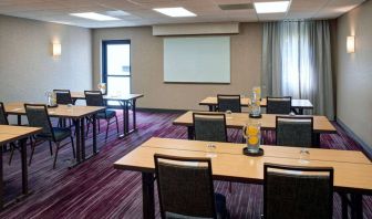 Hotel meeting room with tables, in a classroom format, facing a whiteboard and window.