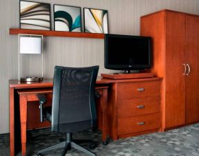 Guest room workspace in Sonesta Select Whippany Hanover, featuring a TV, lamp, desk, and chair.