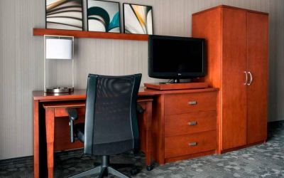 Guest room workspace in Sonesta Select Whippany Hanover, featuring a TV, lamp, desk, and chair.