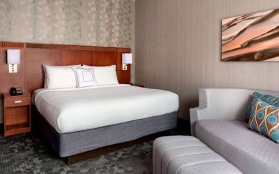 Double bed guest room in Sonesta Select Whippany Hanover with art on the wall and a sofa.