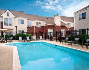 Sonesta ES Suites Annapolis’ outdoor pool has a shaded table and chairs, loungers, and chairs by the side.