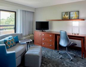 Sonesta Select Raleigh Durham Airport Morrisville guest room living area, furnished with workspace desk and chair, and a sofa and TV.