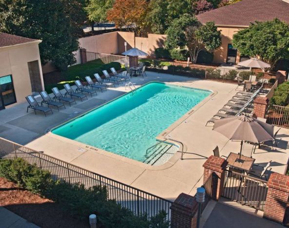The outdoor pool at Sonesta Select Raleigh Durham Airport Morrisville has sun loungers by the side, as well as shaded tables and chairs.