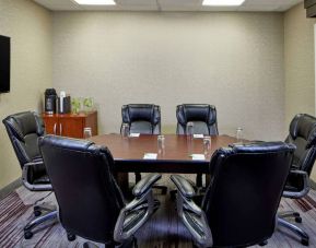 Hotel meeting room, with a wooden table surrounded by six leather chairs, a wall-mounted TV, and a whiteboard.