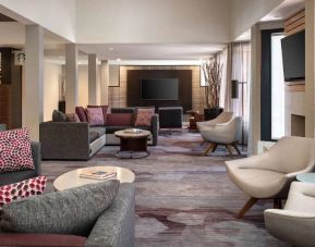 Lounge in the hotel lobby, furnished with comfy chairs and large sofas, coffee tables and multiple large televisions.