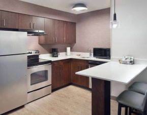 Sonesta ES Suites Raleigh Cary guest room kitchen, fitted with oven, microwave, fridge-freezer, and sink.