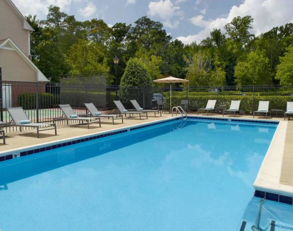 Sonesta ES Suites Raleigh Cary’s outdoor pool has shaded tables and chairs, and numerous sun loungers, by the side.