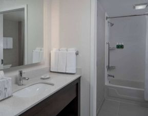 Guest bathroom in Sonesta ES Suites Fairfax Fair Lakes, with shower-equipped bath, mirror, and sink.