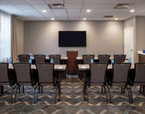 Hotel meeting room, with tables and twelve seats facing a lectern and wall-mounted TV.