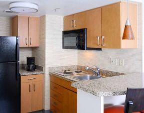 Sonesta ES Suites Dallas Medical Market Center guest room kitchen, with microwave, fridge-freezer, and hob.