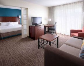 Double bed guest room in Sonesta ES Suites Dallas Medical Market Center, featuring a living area with sofa, armchair, and TV.