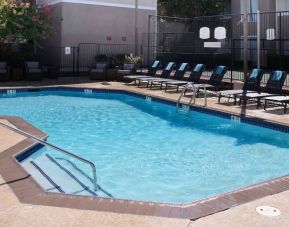 Sonesta ES Suites Dallas Medical Market Center’s outdoor pool has sun loungers as well as armchairs and coffee tables by its side.