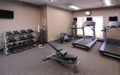 Sonesta ES Suites Dallas Medical Market Center’s fitness center has an assortment of exercise equipment including free weights, and a wall-mounted television.