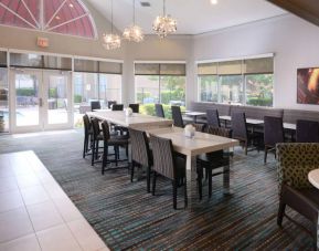 Sonesta ES Suites Dallas Medical Market Center’s lobby is furnished with a mix of table sizes and both regular and tall chairs, with plenty of natural light flowing through large windows.