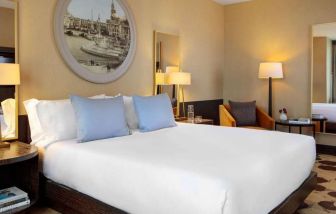 Royal Sonesta Chicago River North double bed guest room, furnished with bedside lamps, coffee table, and an armchair.