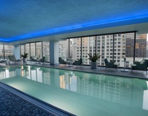 Royal Sonesta Chicago River North’s indoor pool features floor-to-ceiling windows and tables and chairs, and loungers, by the side.